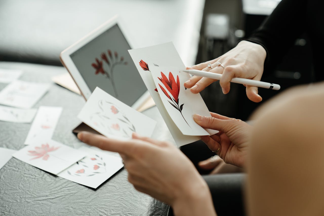 Artists discussing floral tattoo designs using sketches and a digital tablet in a studio.